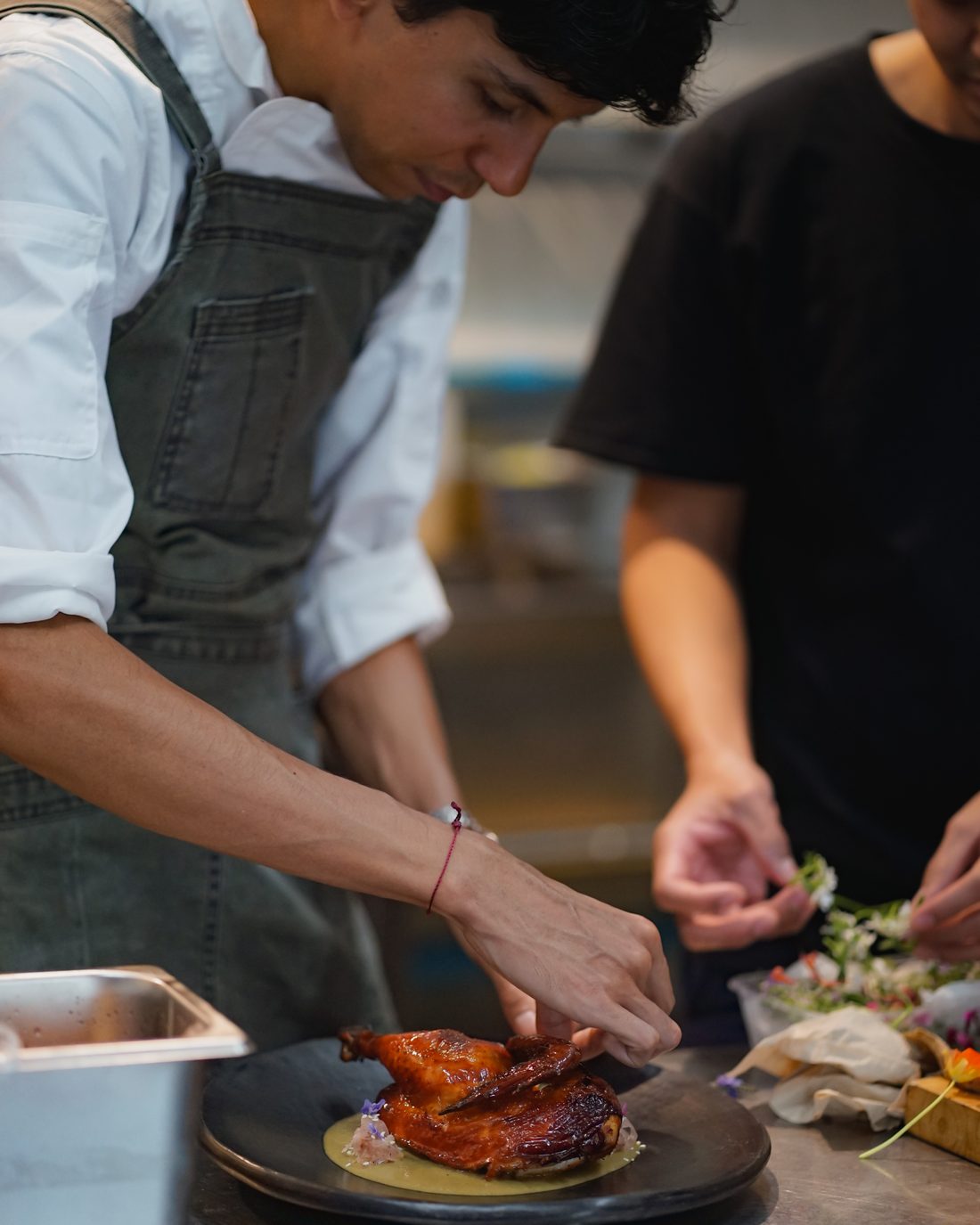 Chef plating wood-roasted chicken at Santiaga